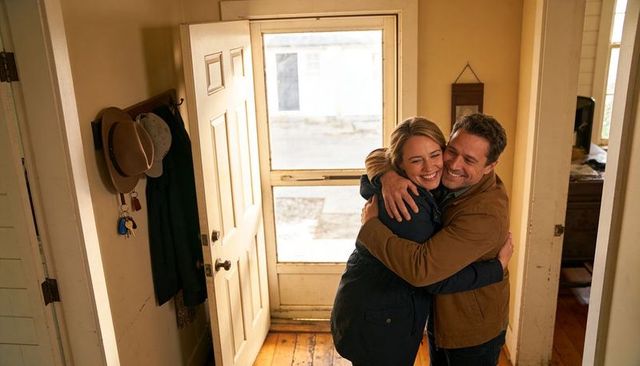Couple embracing in cozy entryway near open door, warm hug celebrating homecoming