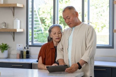 Senior couple using tablet in bright modern kitchen planning together