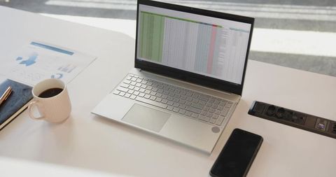 Working on spreadsheet with silver laptop, coffee and smartphone on minimal desk