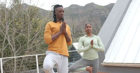 Rooftop Yoga Pair Practicing Tree Pose for Balance, African American Man & Indian Woman