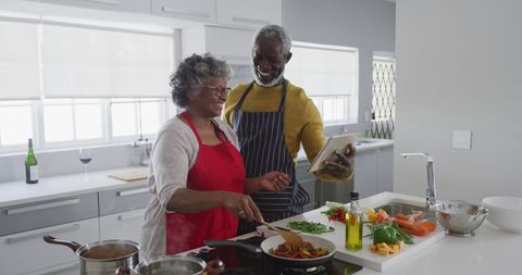 Elderly Couple Cooking Together with Digital Tablet in Kitchen