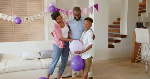 African American family celebrating birthday at home with purple balloons and bunting