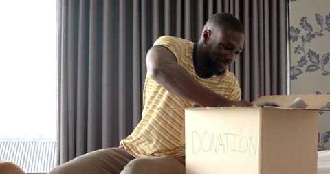 Thoughtful Man Packing Donation Box for Charity with Care