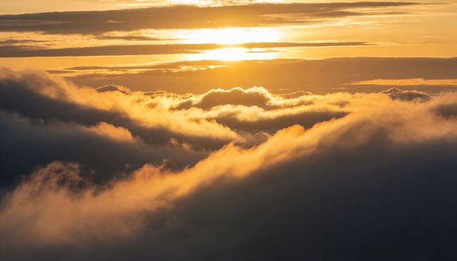 Golden alpenglow glowing over layered stratocumulus and cumulus at sunrise