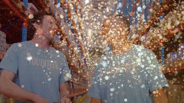 Video shows two volunteers smiling and talking in a warehouse, overlaid with sparkling bokeh effect lights. Ideal for themes related to volunteering, charity, community work, or festive events in workplaces. This can be used in promotional content for charity events, volunteer recruitment campaigns, and community service announcements.