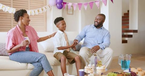 African American family celebrating son's birthday at home with cupcakes and colorful decorations