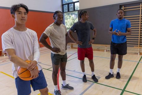 Diverse male basketball players standing on indoor court during team training