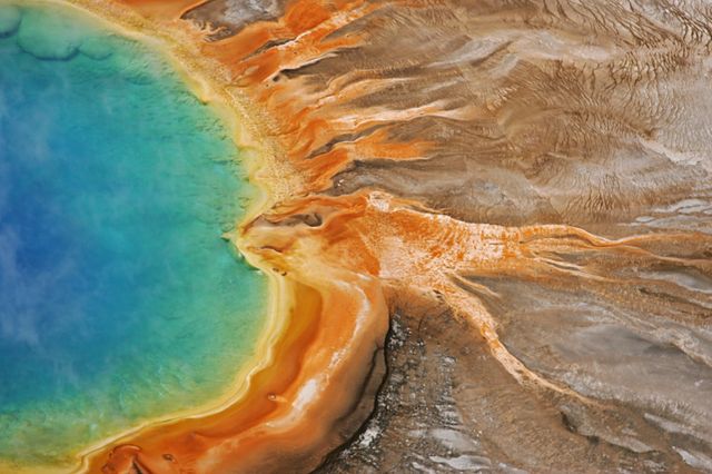Stunning aerial view capturing the vibrant colors of the Grand Prismatic Spring in Yellowstone National Park. Ideal for use in travel magazines, educational materials about geothermal features, or promotional tourism content. Highlights the natural beauty and geological uniqueness of this famous hot spring.