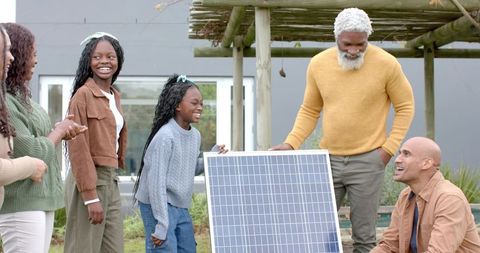 Multigenerational family installing solar panel in backyard celebrating renewable energy