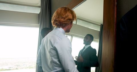 Groom and best man preparing for wedding in bedroom