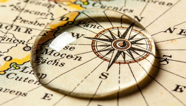 Magnifying dome enlarging vintage compass rose on parchment map with yellow coastline