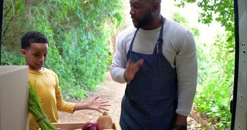 African american man and boy unloading fresh vegetables from van, sharing farm produce