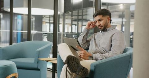 Focused Businessman Reviewing Tablet in Modern Office Lounge