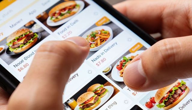 Tapping food delivery app menu on smartphone showing burgers, fries and prices