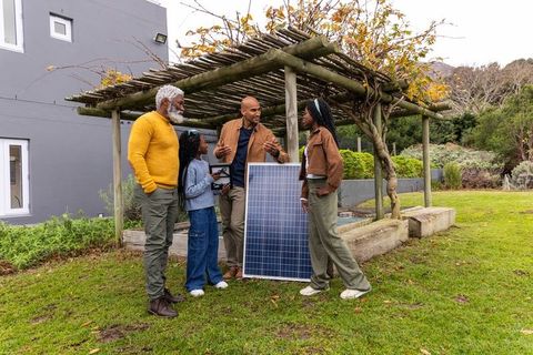 Multigenerational african american family discussing solar panel installation in backyard