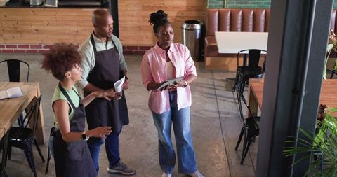 African american cafe team reviewing tablet and planning shift workflow for staff collaboration