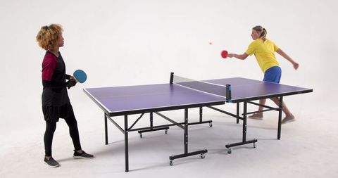 Diverse Female Friends Engaged in Studio Table Tennis Match