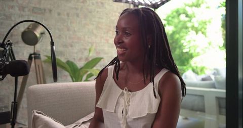 African american woman recording cozy daytime podcast in home studio with microphone