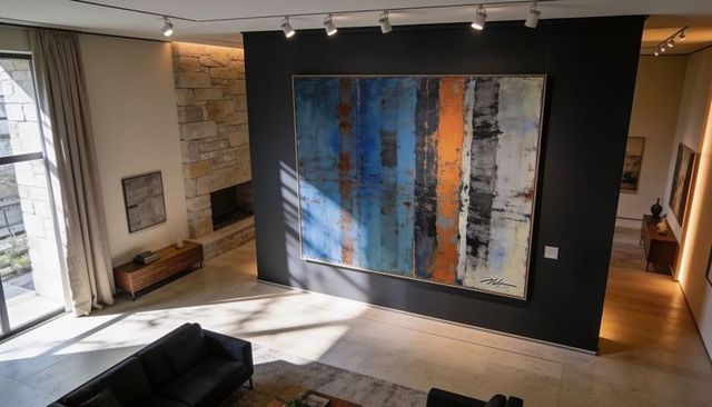 Large abstract painting dominating black accent wall in modern sunlit luxury living room