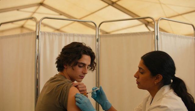 Nurse administering vaccine to young man in temporary clinic tent during immunization campaign