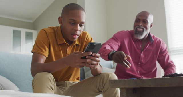 Image of nervous african american father taking his son smartphone and yelling. Parenthood, upbringing and emotions concept.
