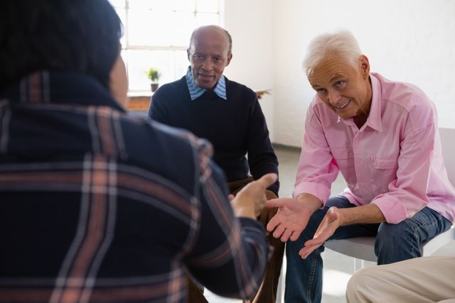 Senior friends are engaging in a lively discussion while sitting in an art class. This image can be used to depict social interaction, community bonding, and active learning among elderly individuals. It is ideal for use in articles or advertisements related to senior activities, community centers, and creative workshops.