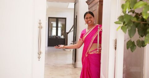 Smiling indian woman in sari welcoming guests into home