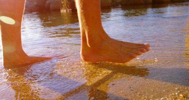 Feet of caucasian man walking in water on sunny beach. Summer, lifestyle, travel and vacations.