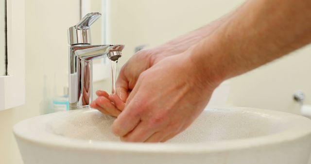 Caucasian man washing hands in a bathroom sink. Proper hygiene practices are essential for maintaining health and preventing illness.