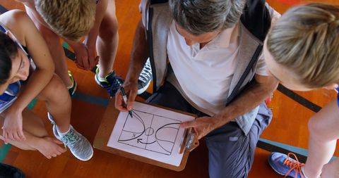 Coach explaining basketball strategy to youth athletes