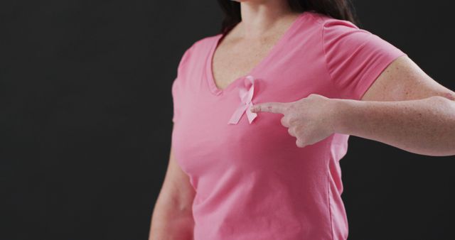 Woman Wearing Pink T-Shirt Pointing at Breast Cancer Awareness Ribbon - Download Free Stock Images Pikwizard.com