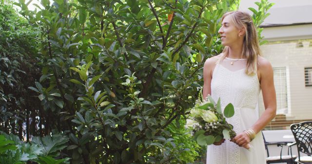 Happy caucasian woman holding bunch of flowers in garden on sunny day. wedding day and celebration concept.