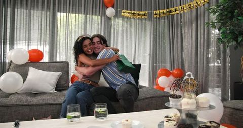 Diverse couple celebrating birthday with gifts in cozy living room