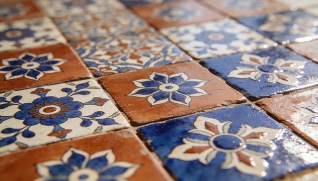Glazed cobalt terracotta floral ceramic tiles reflecting warm light on kitchen backsplash