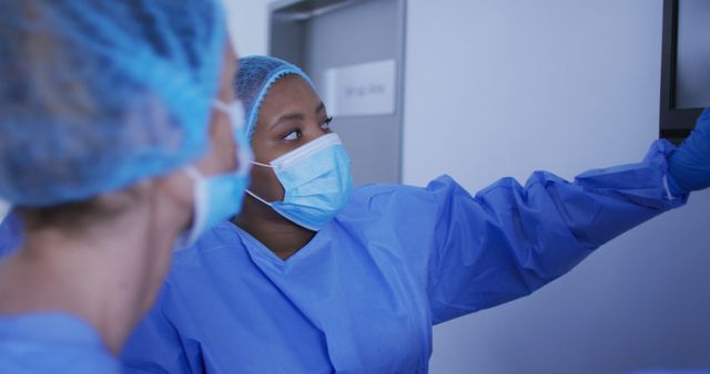 Health professionals wearing masks and scrubs are discussing a medical procedure in a hospital room. This can be used in articles or websites highlighting healthcare teamwork, medical procedures, hospital environments, and patient care safety protocols.