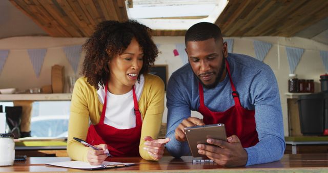 African american couple smiling while using digital tablet in food truck. food truck and street food concept