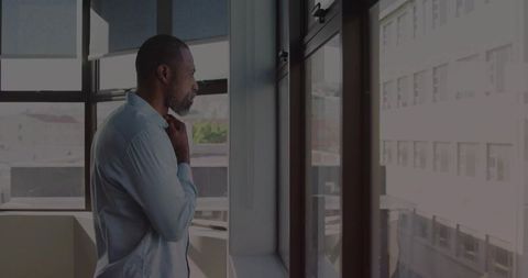 Businessman adjusting collar in modern office with urban view