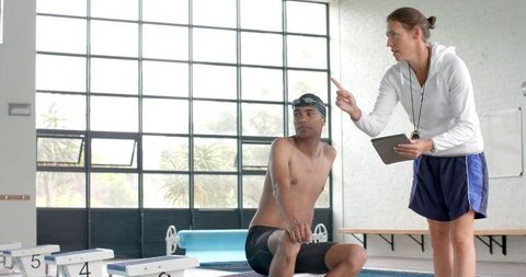 Swimming Coach Giving Athlete Instruction at Poolside