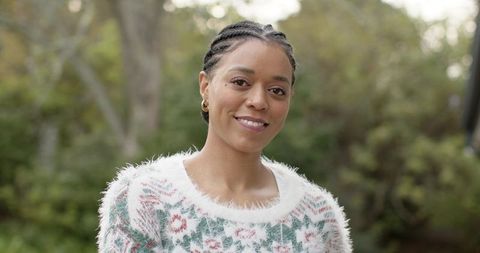 Smiling mid adult woman wearing cozy fuzzy patterned sweater, braided hair, hoop earrings