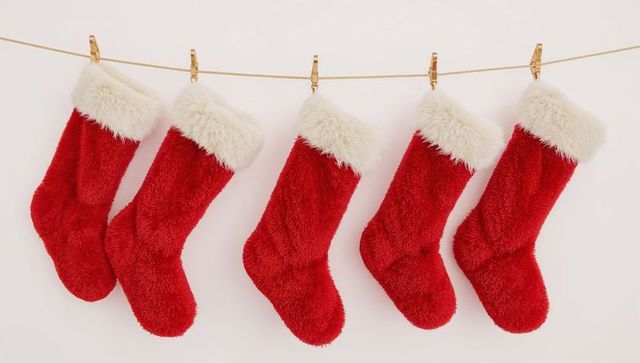 Five red plush christmas stockings hanging on gold cord with white fur cuffs
