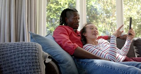 Happy Couple Relaxing on Couch Using a Tablet in Living Room