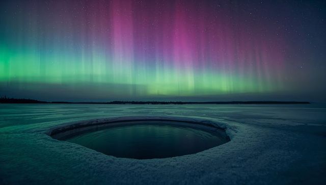 Majestic aurora borealis over frozen lake with ice hole