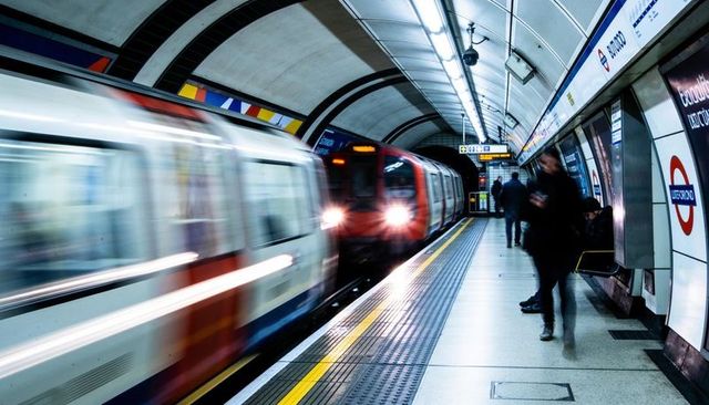 Red subway train departing underground platform with commuters and motion blur