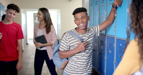 Happy Teenage Boy Smiling at School Locker in Lively Hallway Scene