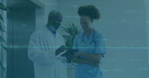 Healthcare Professionals Analyzing Data on Tablet in Hospital Corridor