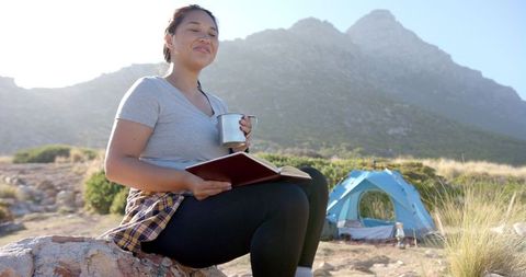 Woman Enjoying Nature Reading Book Near Tent Mountain View