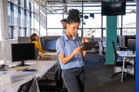 Young professional using tablet in modern open office with collaborative team