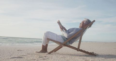 Senior Woman Relaxing on Beach with Book at Sunset