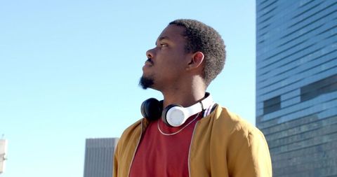 African American man gazing at skyline wearing headphones and mustard jacket portrait