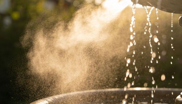 Glistening backlit fountain mist sparkling with golden droplets at sunset garden bokeh